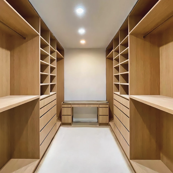 Custom walk-in closet with light wood cabinetry and built-in storage